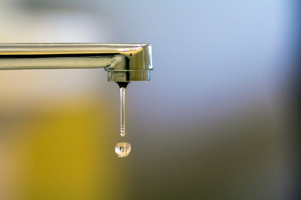 Close-up of faucet with turned drop water in modern bathroom.